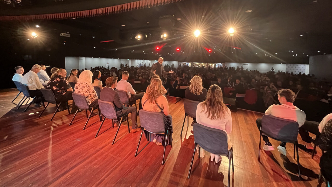 Comedy hypnotist Gerard V and volunteers perform on stage at a large corporate gala dinner